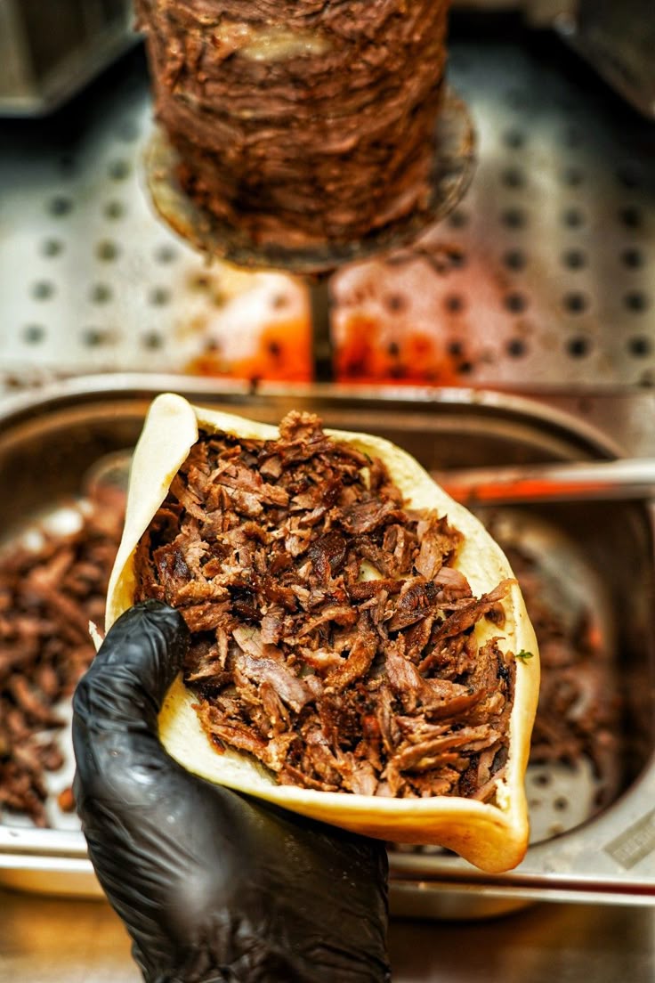 Pain pita ouvert rempli de viande de kebab devant la broche